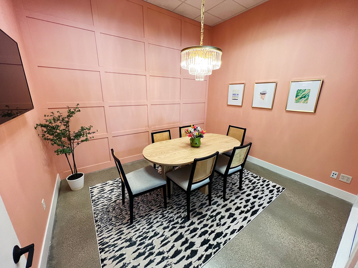 pink conference room with black and white rug and a table for six